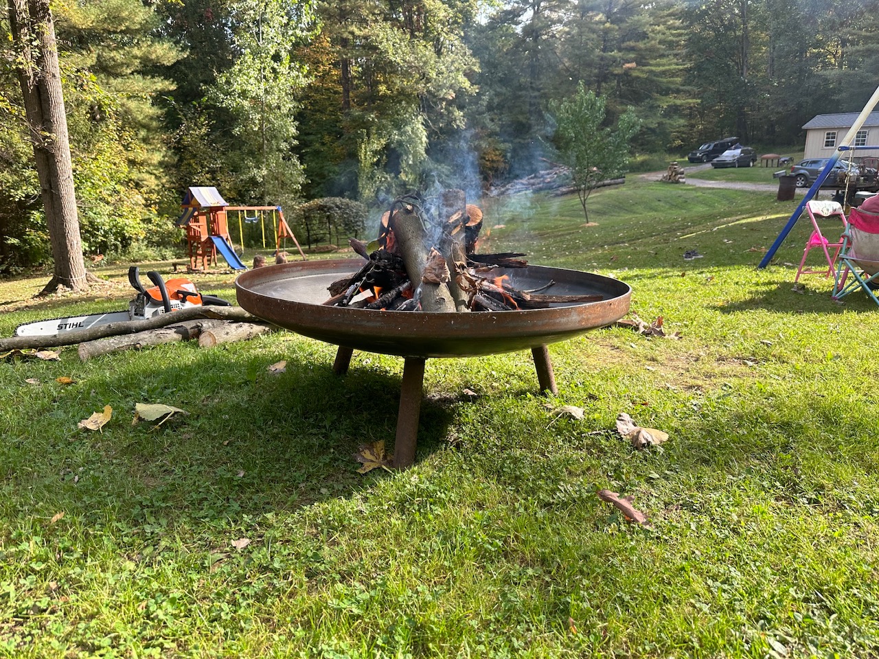 Heavy steel fire pit burning at dusk on a gravel patio in the Virginia countryside